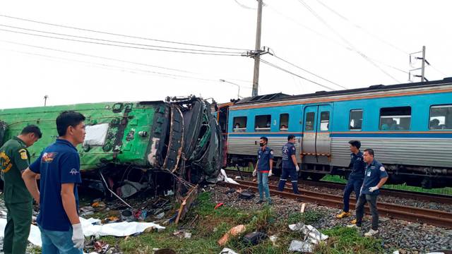 Rescue workers stand at the crash site where a train collided with a paseengers bus in Chacheongsao province in central Thailand