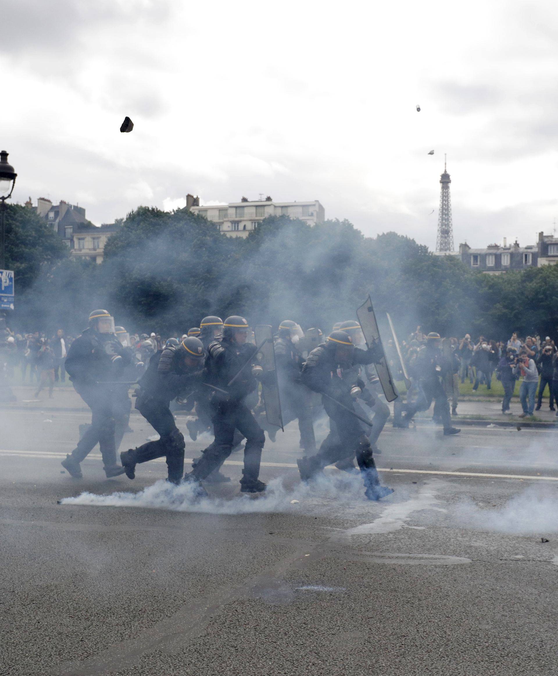 French CRS riot police protect themselves from flying debris during clashes with demonstrators at the Invalides square during a demonstration in Paris 