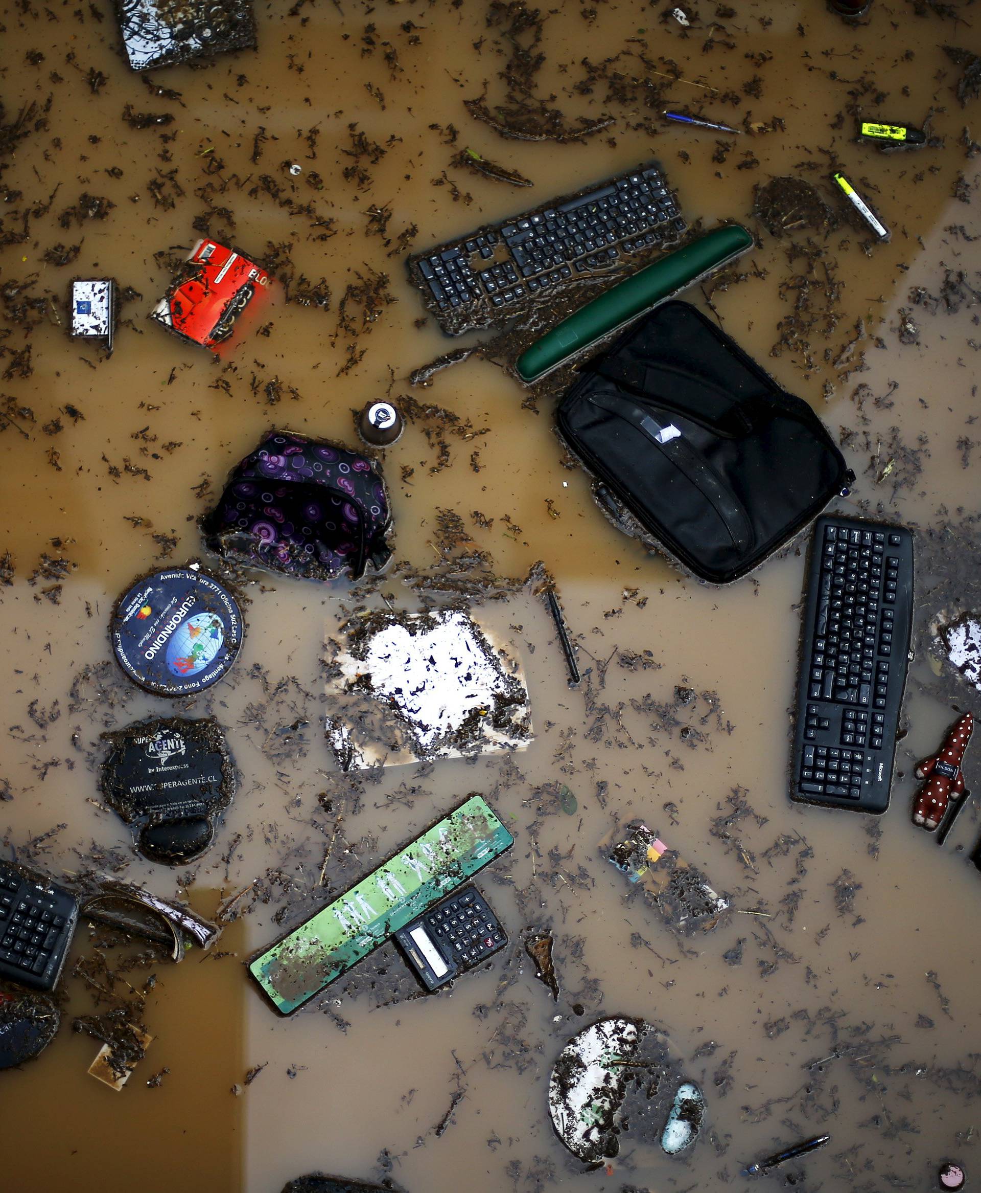 Keyboards and office supplies are seen in a street after floods in Santiago