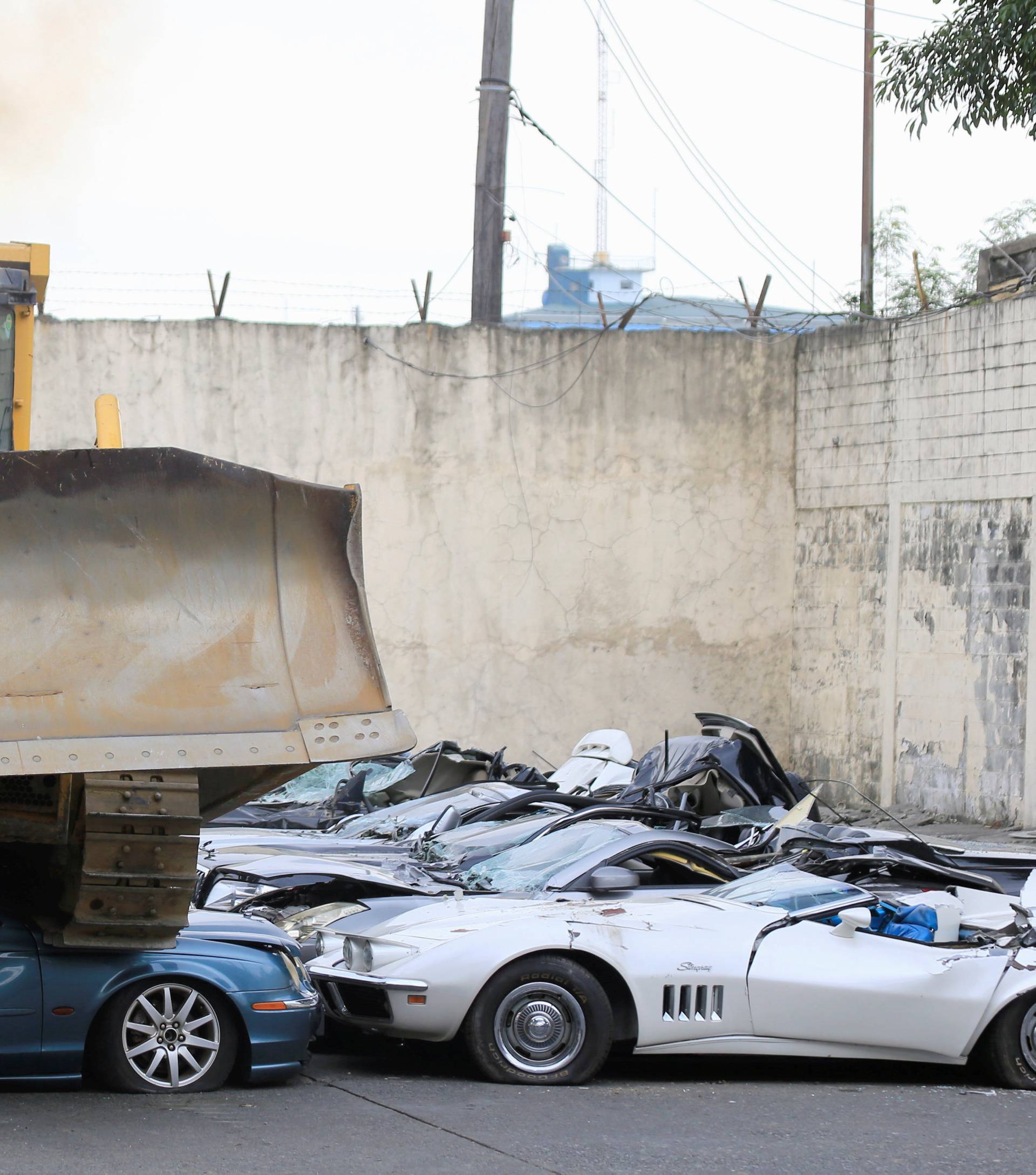 A bulldozer destroys condemned smuggled luxury cars worth 61,626,000.00 pesos during the 116th Bureau of Customs founding anniversary in Manila