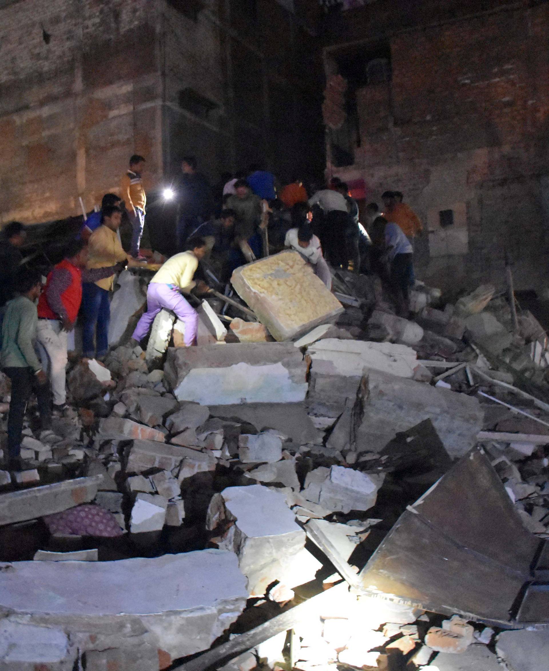 People remove the debris as they search for survivors at the site of a collapsed hotel building in Indore