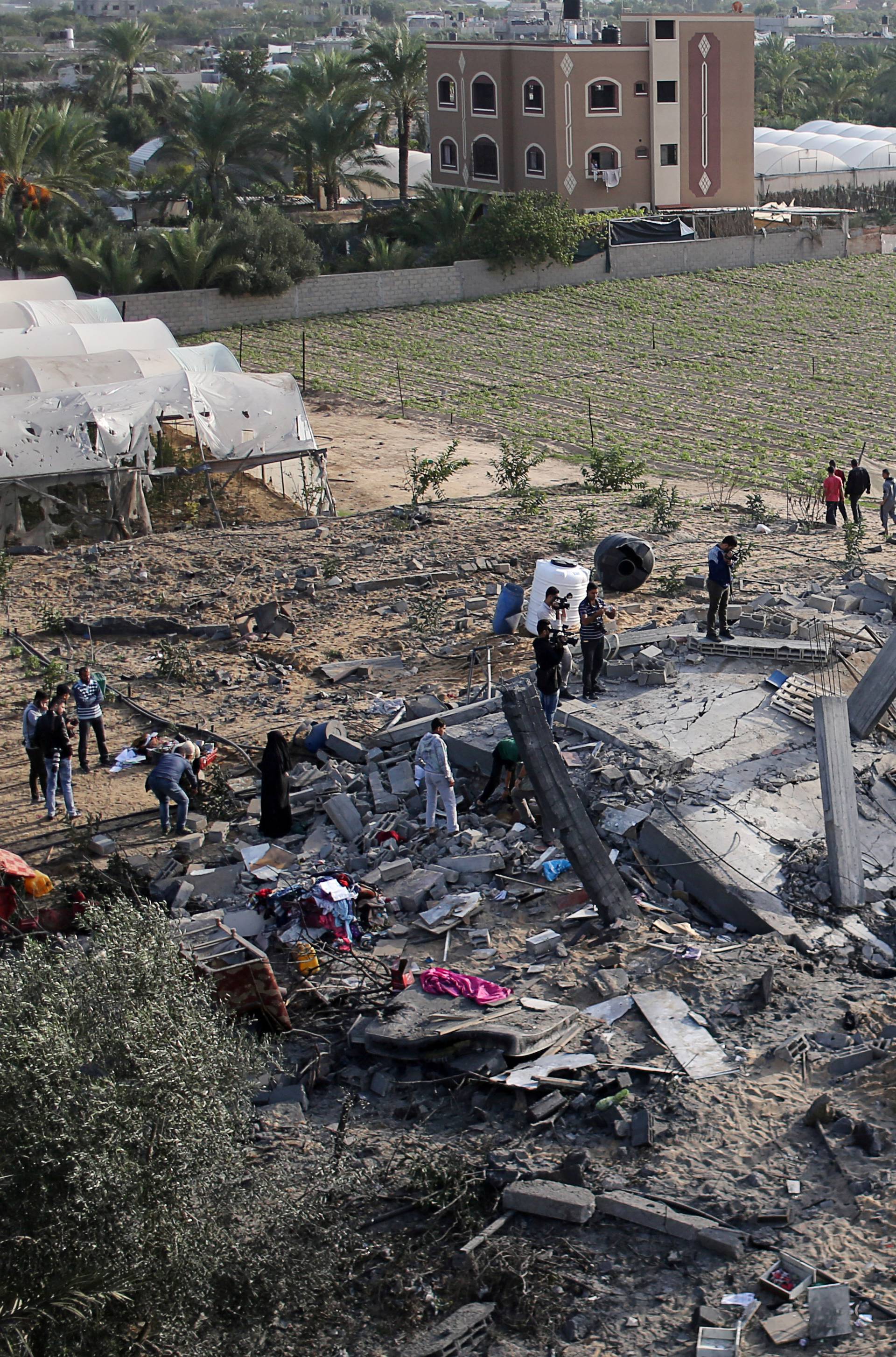 Palestinians gather around the remains of a house destroyed in an Israeli air strike in the southern Gaza Strip