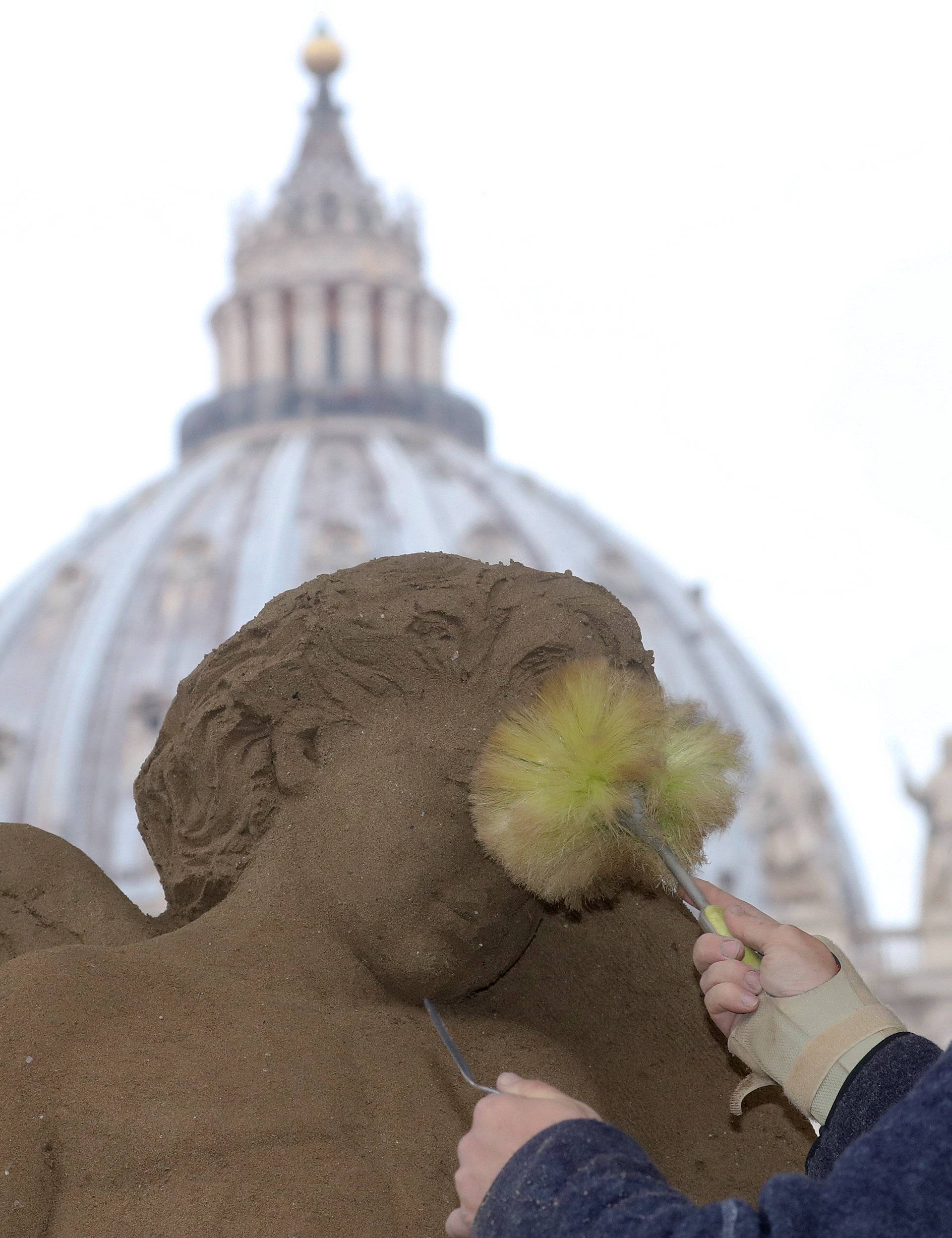 An artist works on a sand sculpture representing part of nativity scene in St. Peter's square at the Vatican