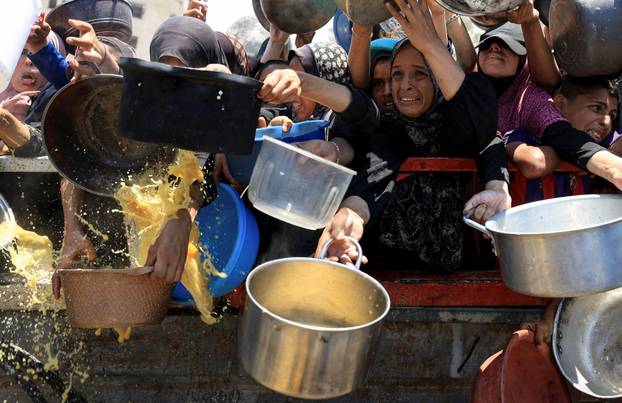 Palestinians wait to receive food from a charity kitchen, in Gaza City
