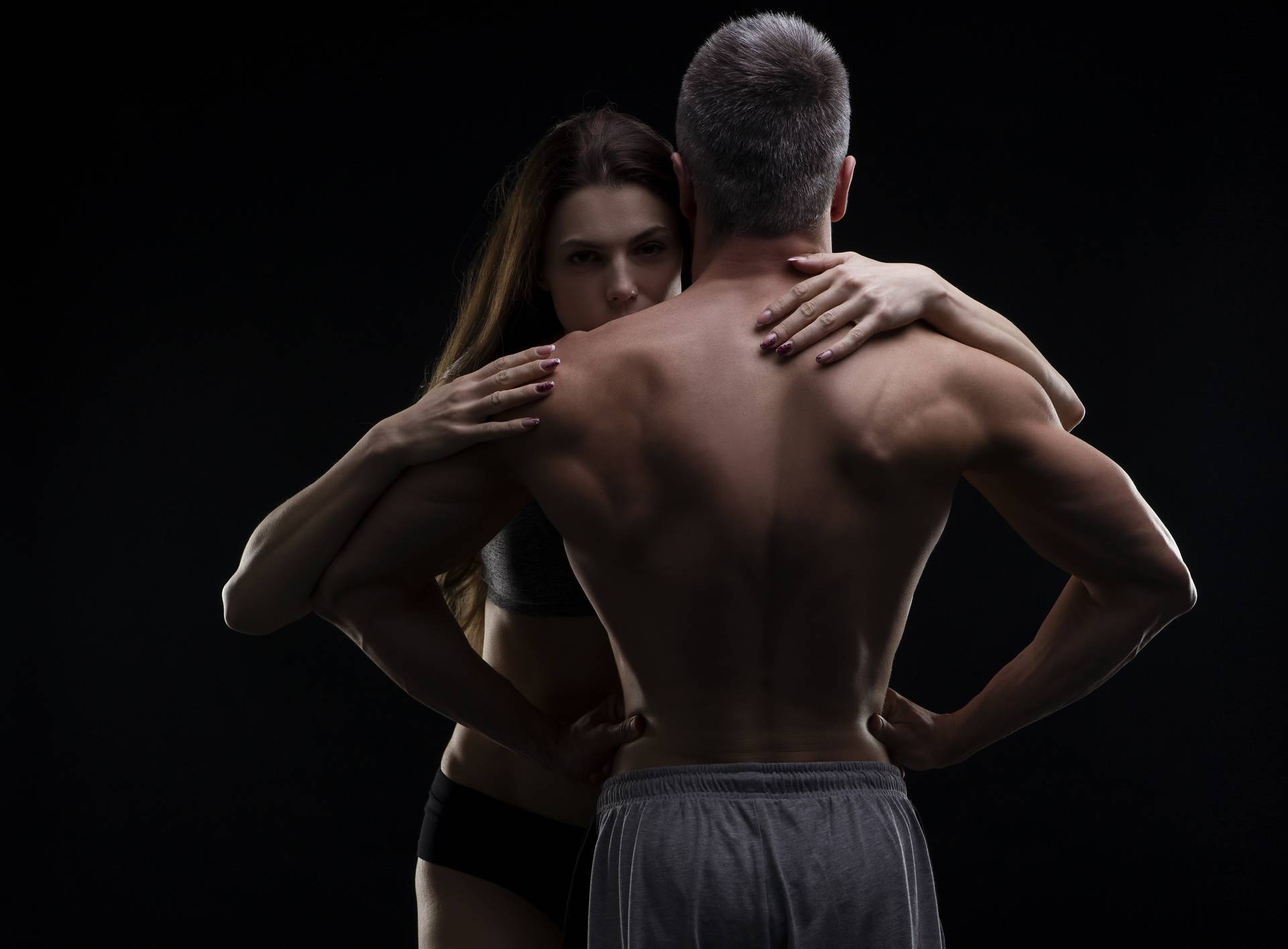 Young adult muscular man and woman. Sexy couple on black background