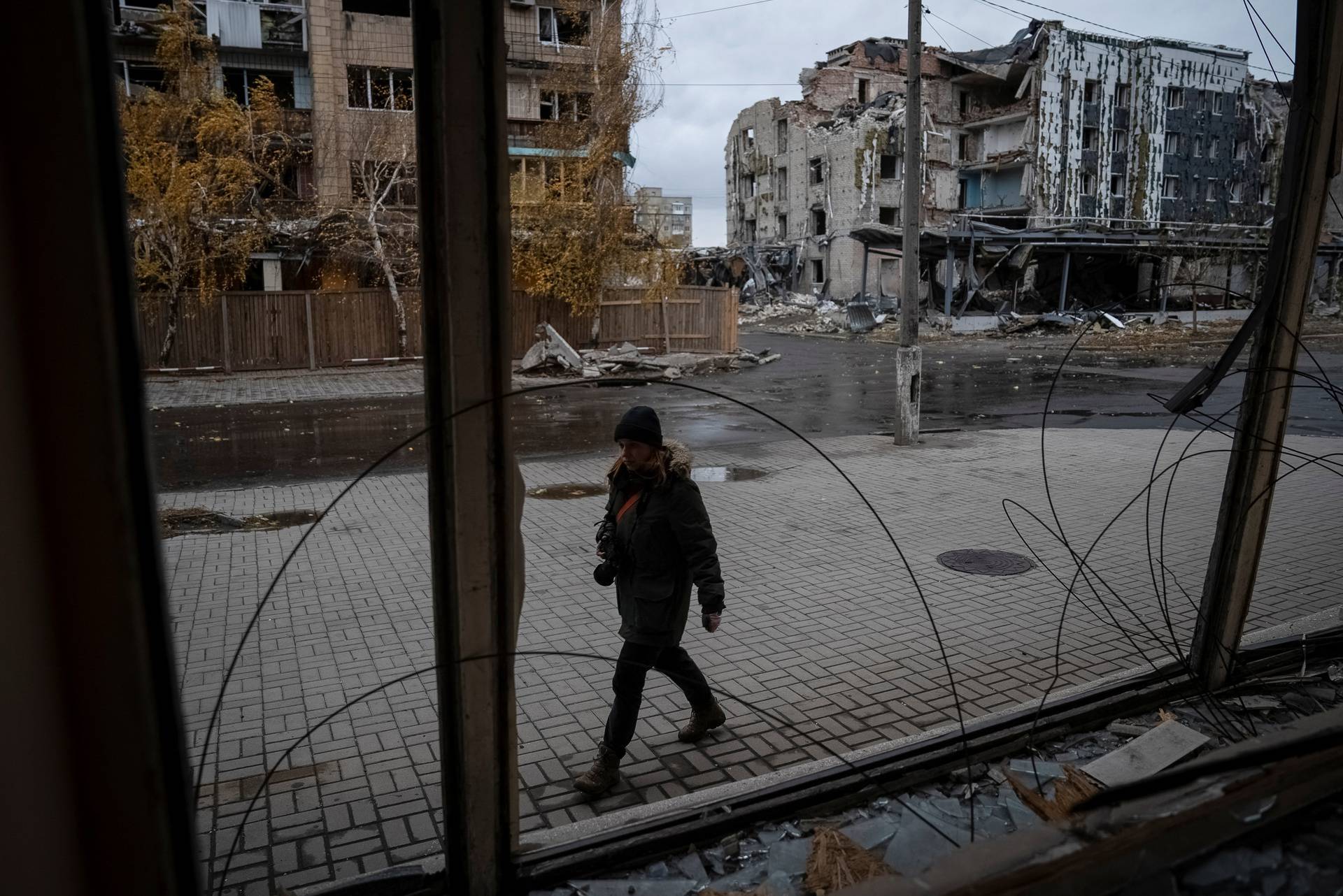 A photographer walks past buildings damaged by a Russian military strike in the town of Pokrovsk