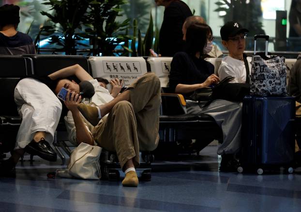 Passengers rest at Haneda Airport as many flights are delayed and cancelled due to Typhoon Dujuan, in Tokyo