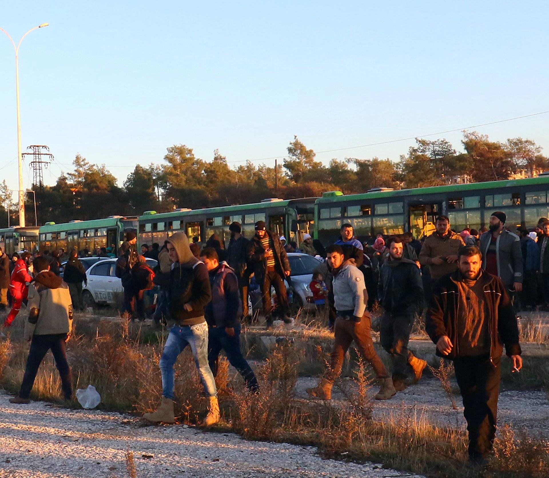 Evacuees from rebel-held east Aleppo, disembark from buses upon their arrival to the town of al-Rashideen