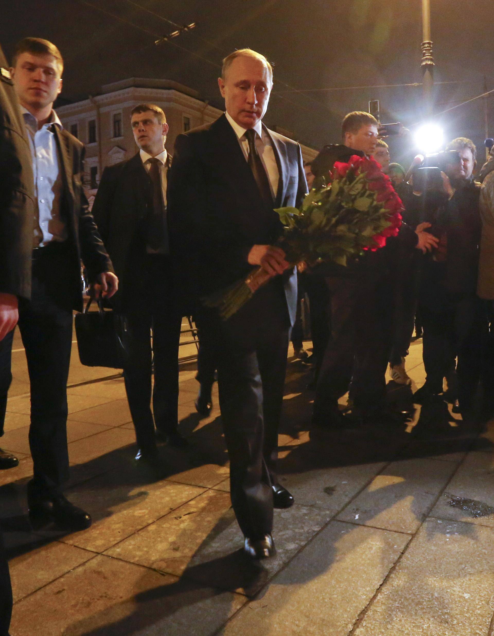 Russian president Vladimir Putin puts flowers down outside Tekhnologicheskiy Institut metro station in St. Petersburg
