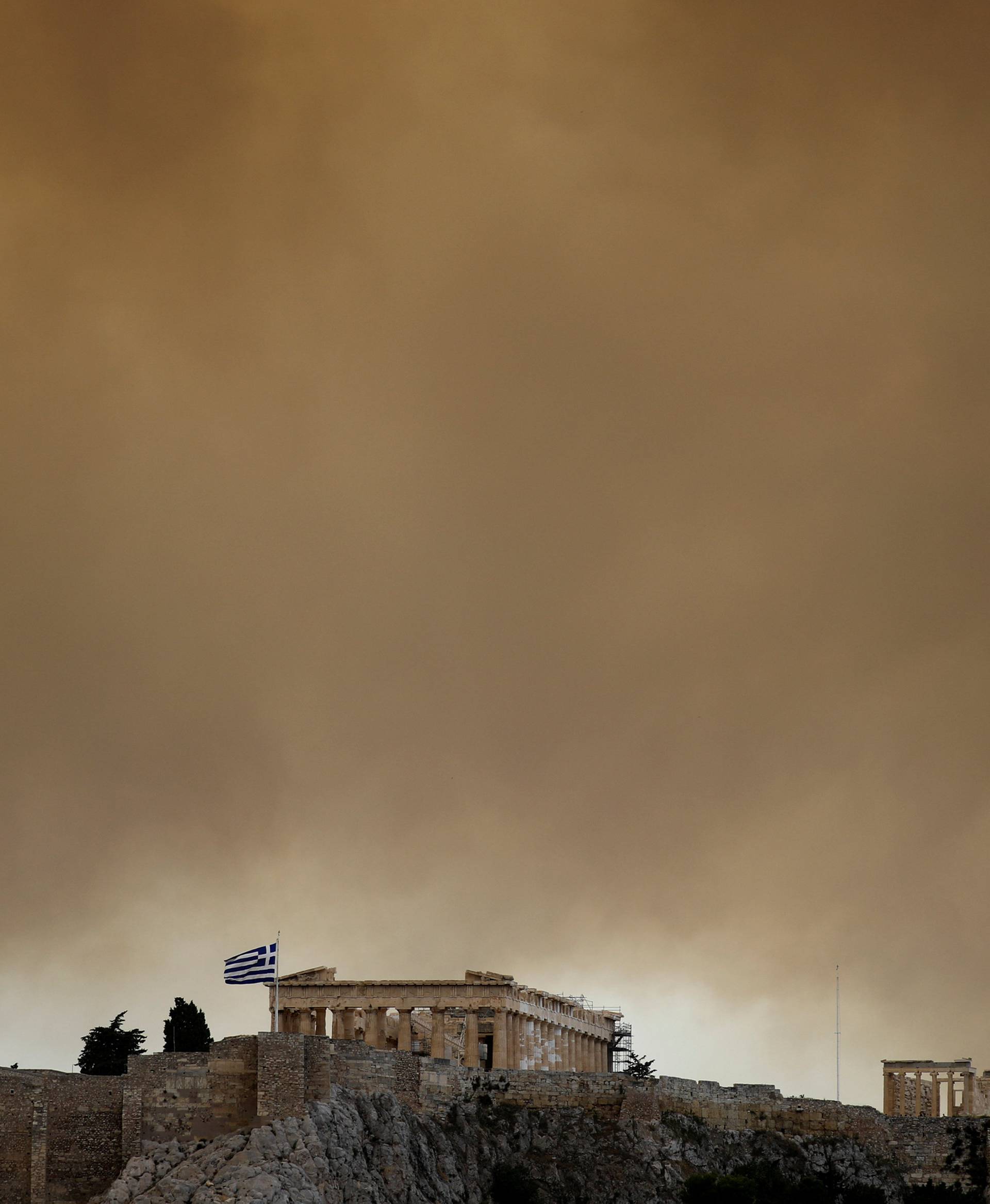 Smoke from a wildfire burning outside Athens is seen over the Parthenon temple atop the Acropolis hill in Athens