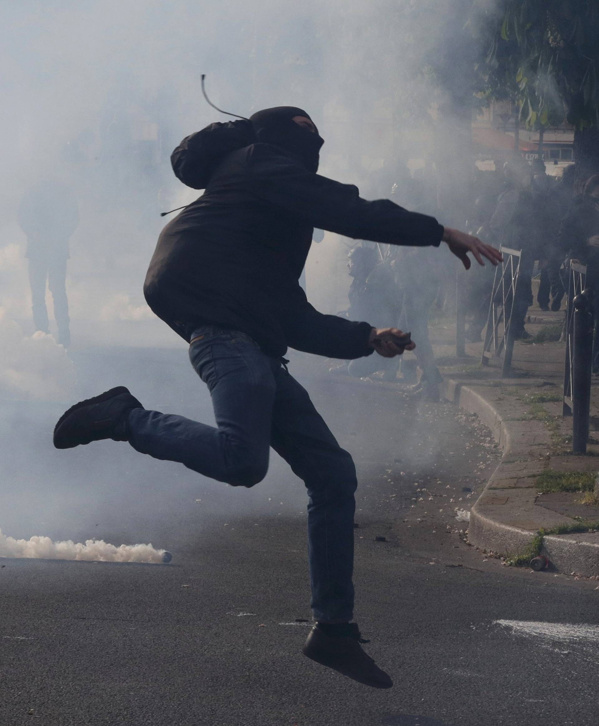 A masked youth runs through a cloud of tear gas during clashes with gendarmes and police during a demonstration against the French labour law proposal in Paris