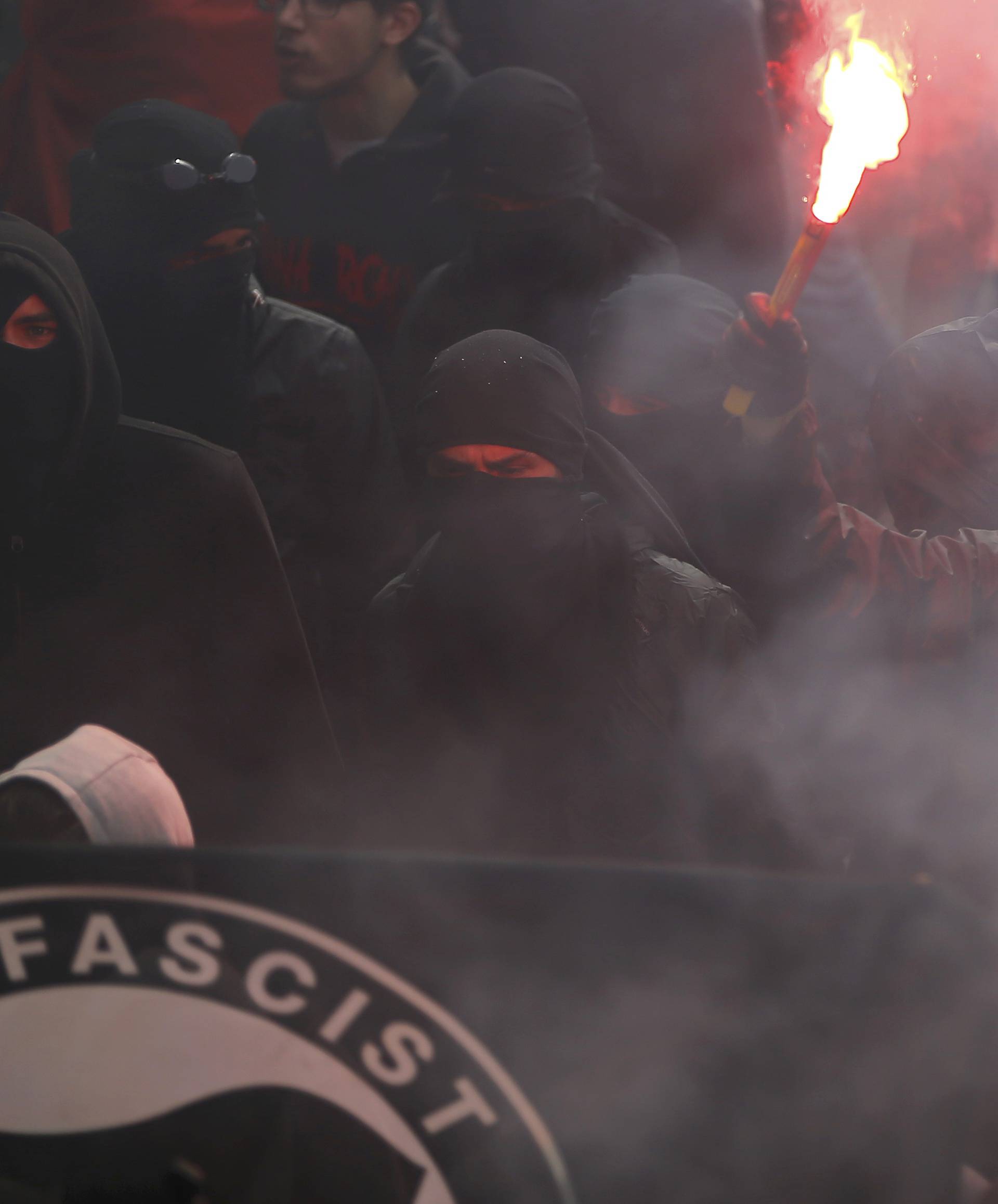 Masked protesters light a flare as they take part in a march in Nantes to demonstrate against the new French labour law
