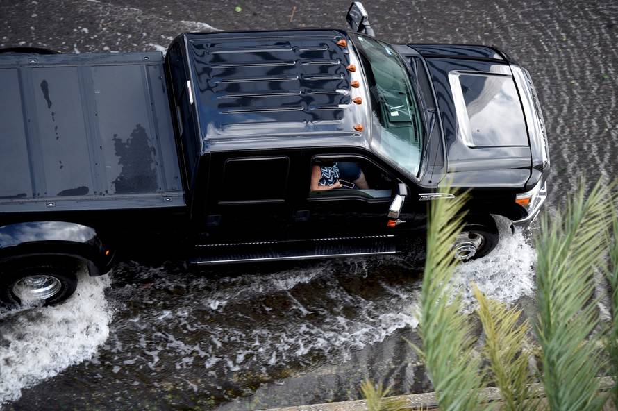 A woman uses her phone while driving through floodwaters after Hurricane Irma