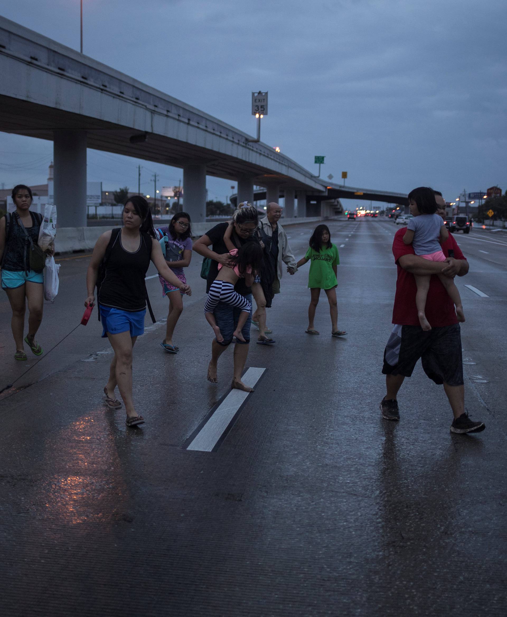 The Duong family, with children, parents and dog in tow, walks along Interstate 45 while escaping flood waters from Tropical Storm Harvey in Houston