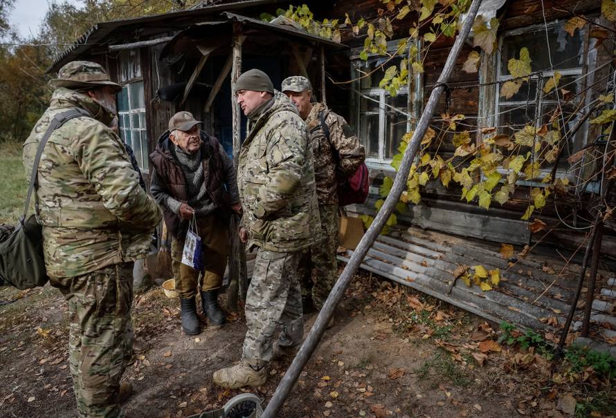 Ivan Troyanok speaks with servicemen near his house in a Chornobyl exclusion zone village