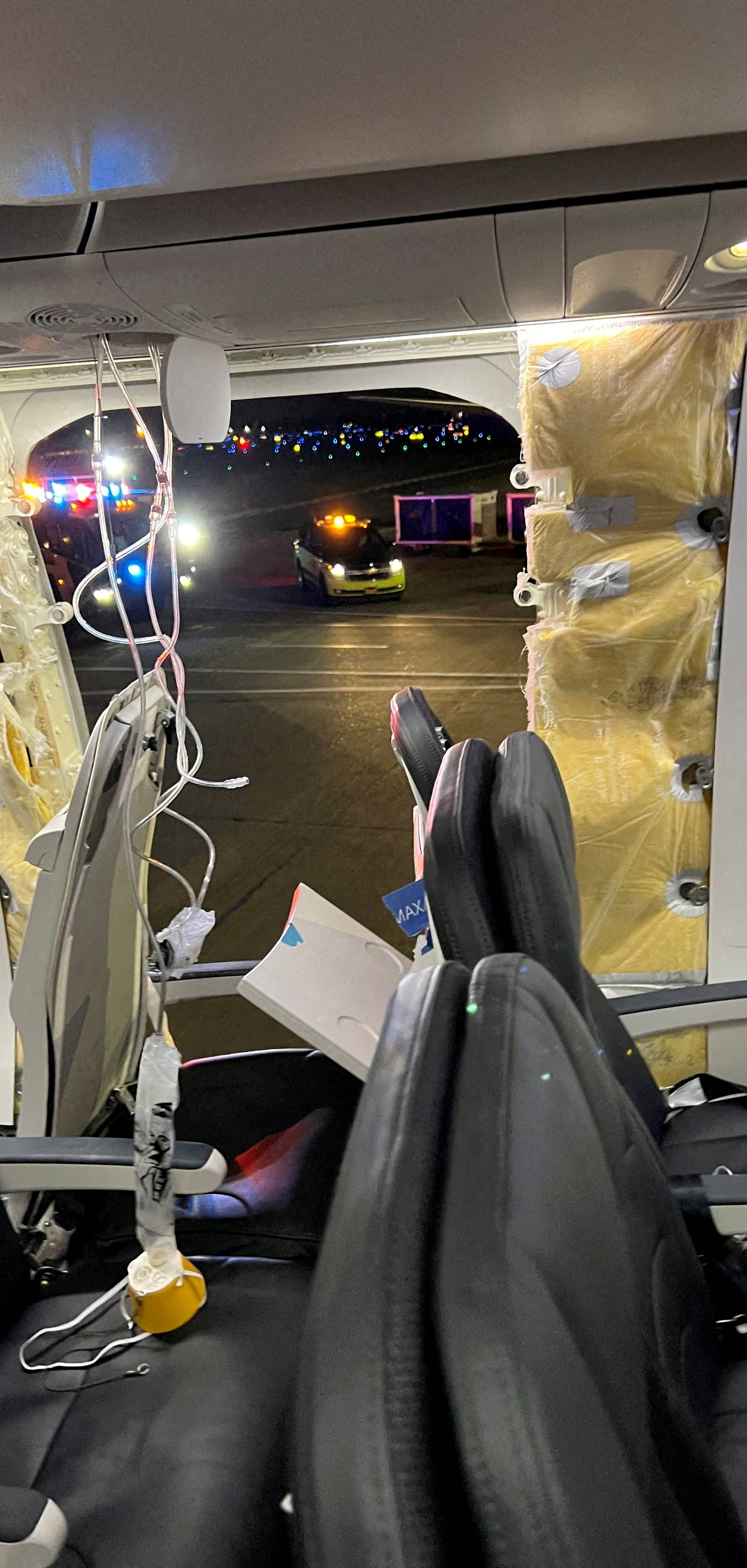 FILE PHOTO: Passenger oxygen masks hang from the roof next to a missing window and a portion of a side wall of an Alaska Airlines Flight 1282, in Portland, Oregon