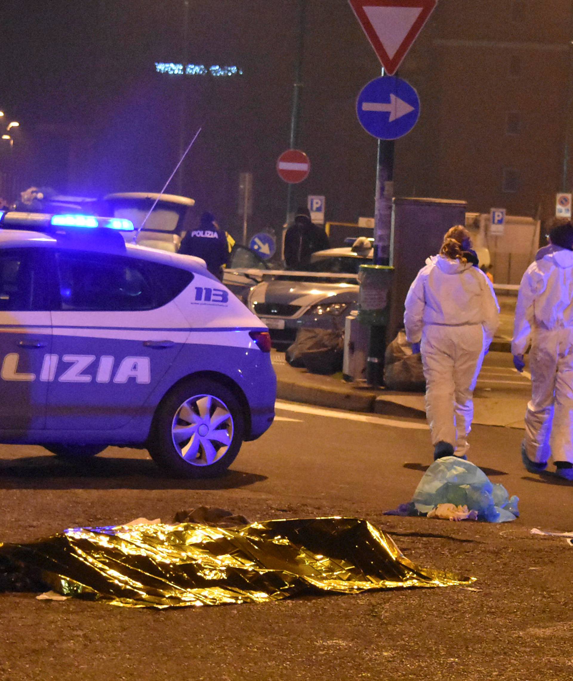 The body of Anis Amri, the suspect in the Berlin Christmas market truck attack, is seen covered with a thermal blanket next to Italian officers in a suburb of the northern Italian city of Milan