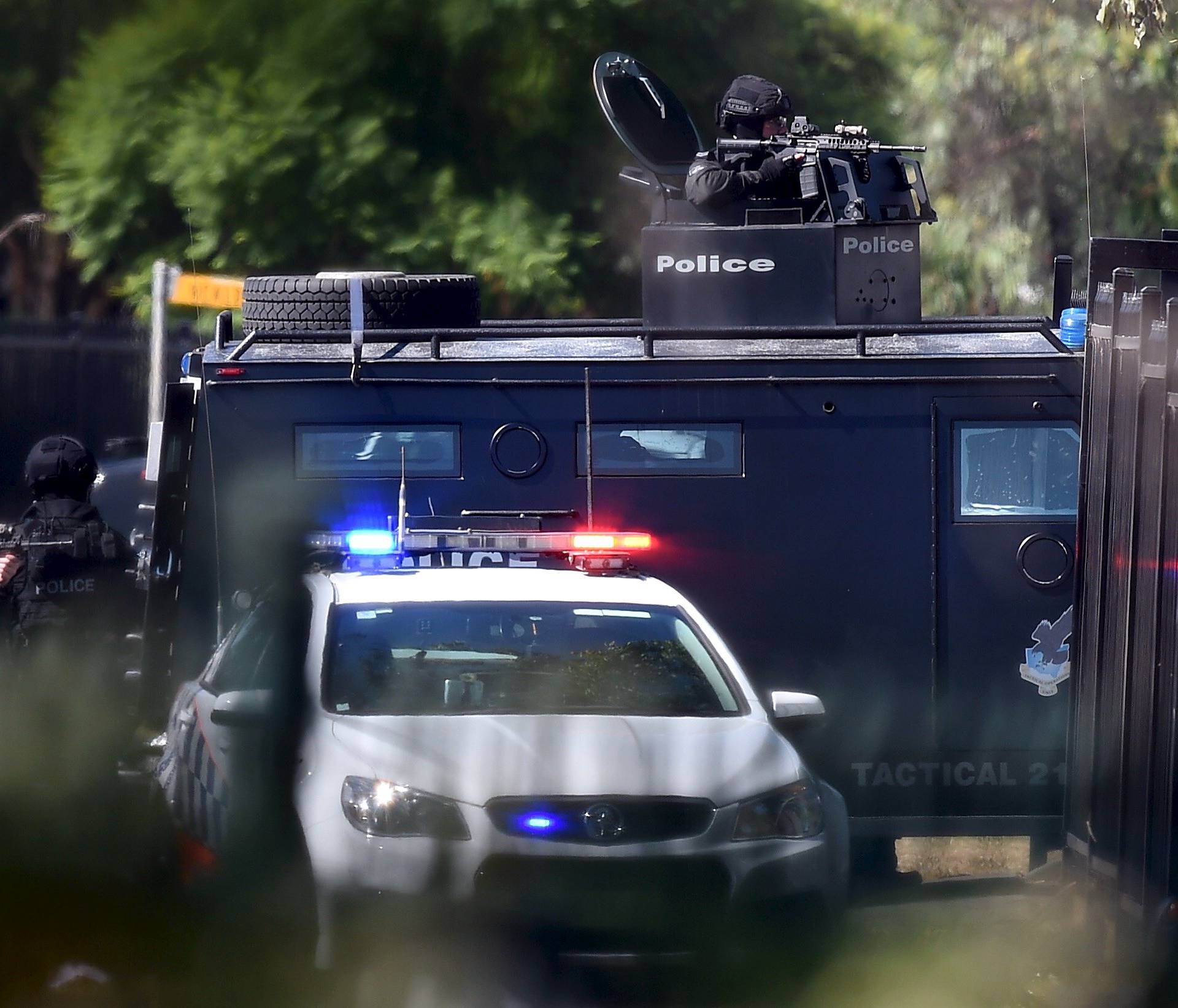 Heavily armed tactical police officers aim their weapons at the scene of a shooting in the western Sydney suburb of Ingleburn, Australia