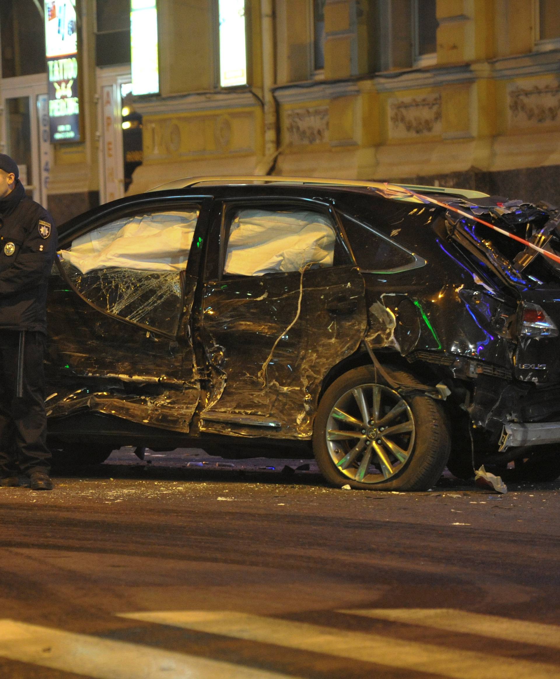 Policemen stand next to a damaged sport utility vehicle (SUV) at the accident scene after a car drove into pedestrians following a vehicle collision in central Kharkiv