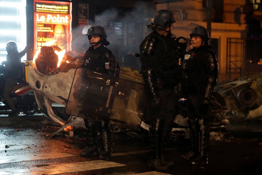 French riot police stand near an overturned burning car on avenue Kleber after clashes with protesters wearing yellow vests, a symbol of a French drivers' protest against higher diesel taxes, in Paris