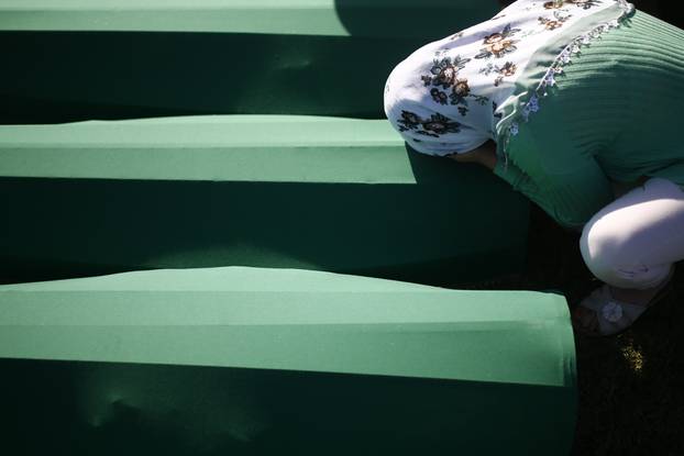 A woman mourns near coffins of her relatives, who are newly identified victims of the 1995 Srebrenica massacre, which are lined up for a joint burial in Potocari near Srebrenica