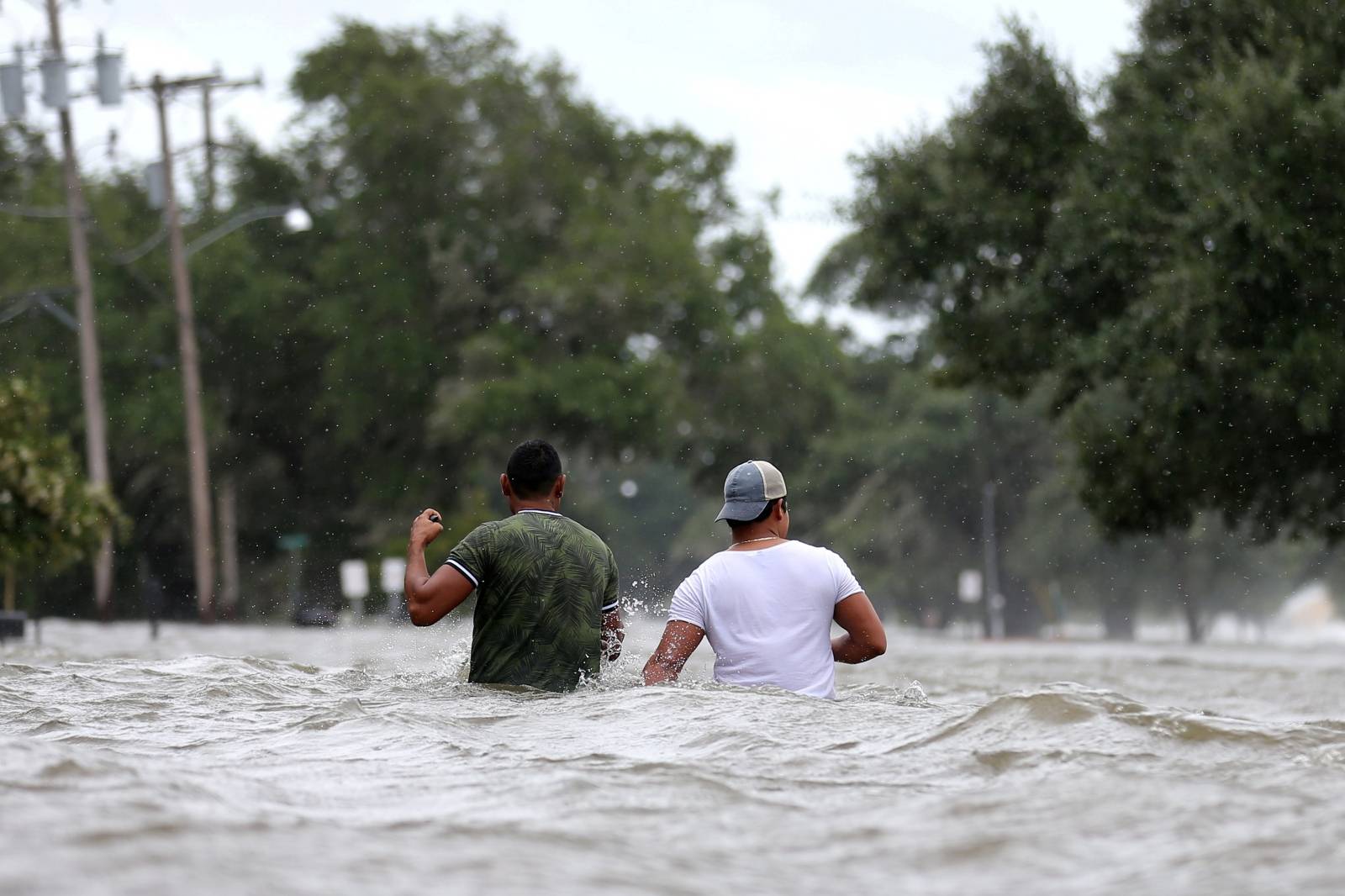People wade through a flooded street after Hurricane Barry in Mandeville