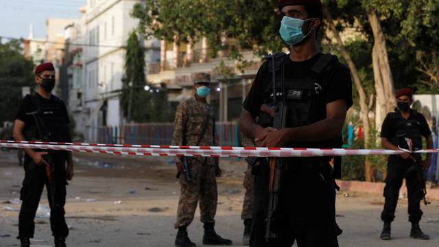 Police officers guard a cordoned-off street leading to the site of a passenger plane crash in a residential area near an airport in Karachi,