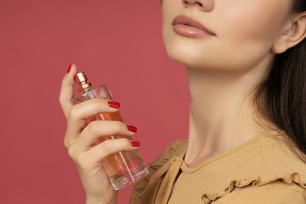 Beautiful bottle with perfume in hand close-up