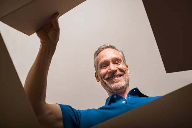 Happy,Mature,Man,Looking,Into,Parcel,Cardboard,Box,And,Smiling.