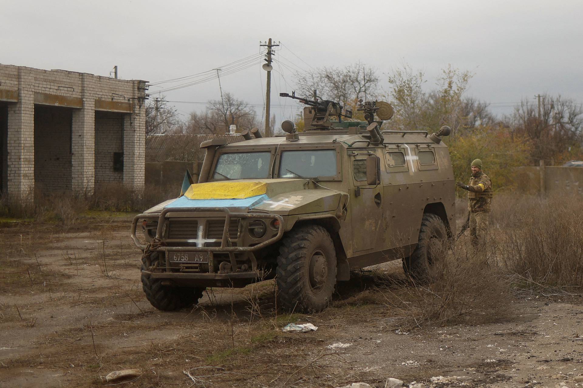 Ukrainian service member stands next to a previously captured Russian armoured personnel carrier in the village of Blahodatne in Kherson region