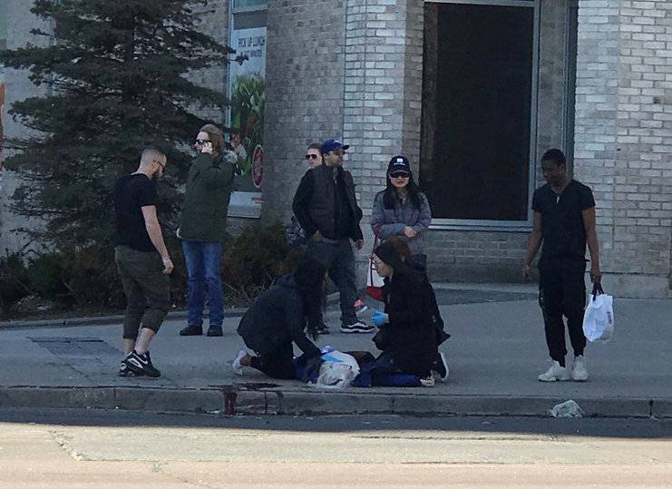 A victim is helped by pedestrians after a van hit multiple people at a major intersection in Toronto
