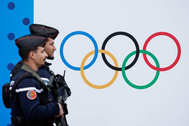 French Gendarmes walk past the logo of the Paris 2024 Olympic and Paralympic Games in front of the National Assembly in Paris