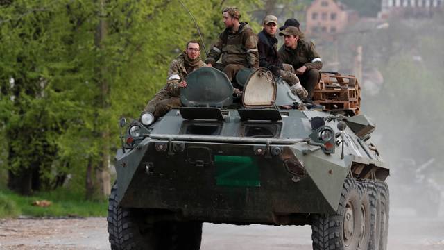 Service members of pro-Russian troops ride an armoured personnel carrier in Mariupol