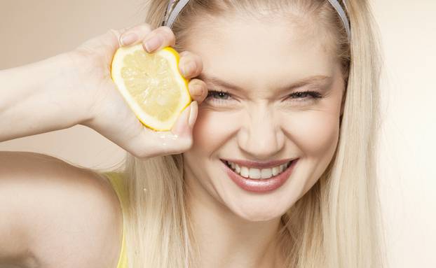 Young woman squeezing lemon, studio shot