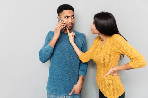 Woman pointing at phone of her husband with claim