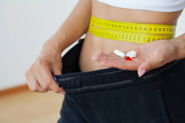 Woman,Measuring,Her,Waist,With,Many,Slim,Pills,In,Her