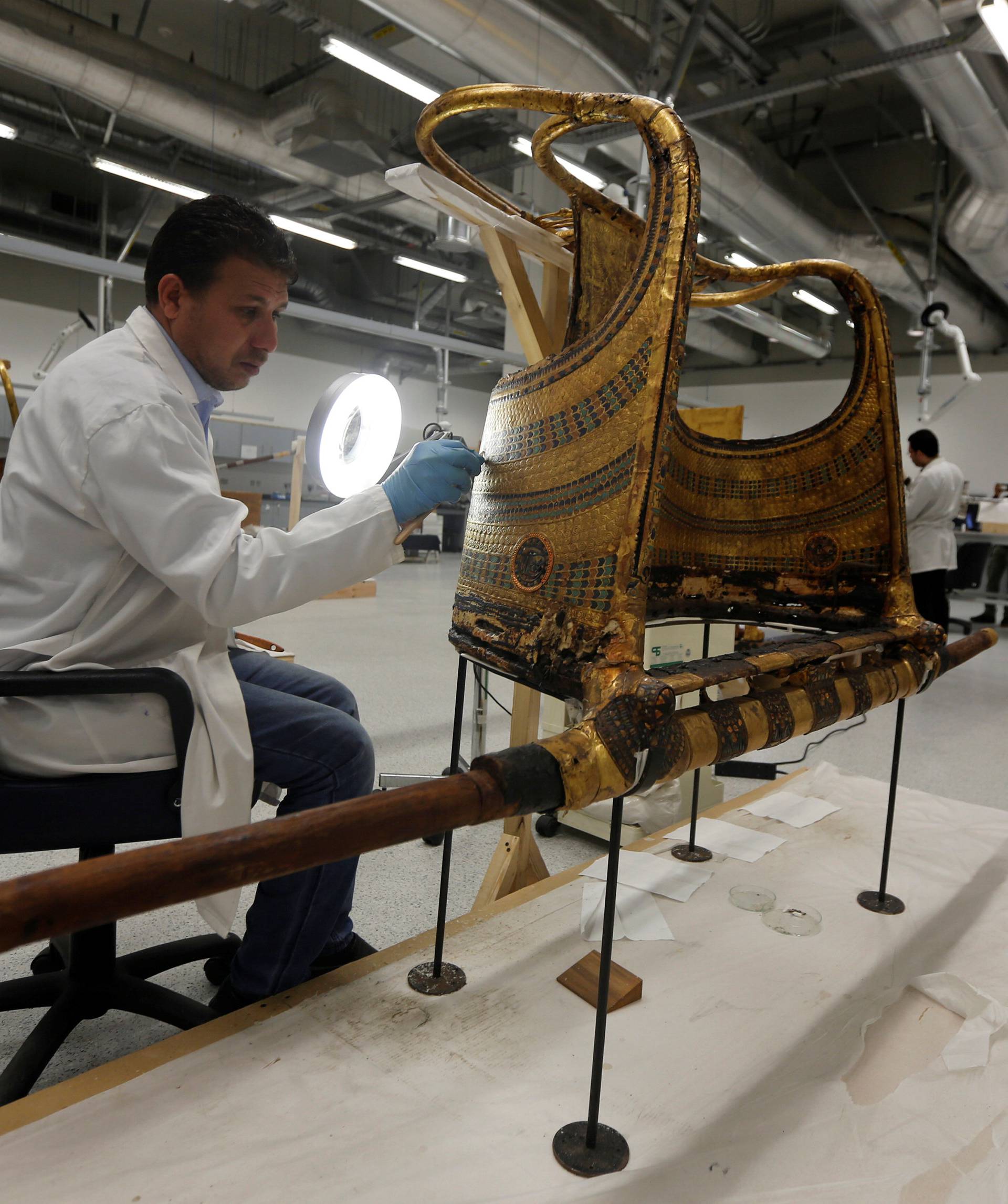 An Egyptian archaeological technician renovates the golden war wheel which belonged to King Tutankhamun, in the conservation centre of the Grand Egyptian Museum, on the outskirts of Cairo