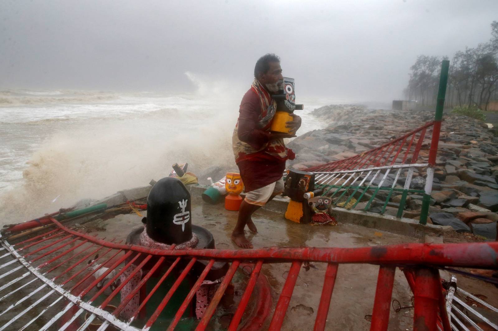 A Hindu priest carries an idol of Lord Jagannath from a seafront temple to a safer place ahead of Cyclone Yaas in Balasore district