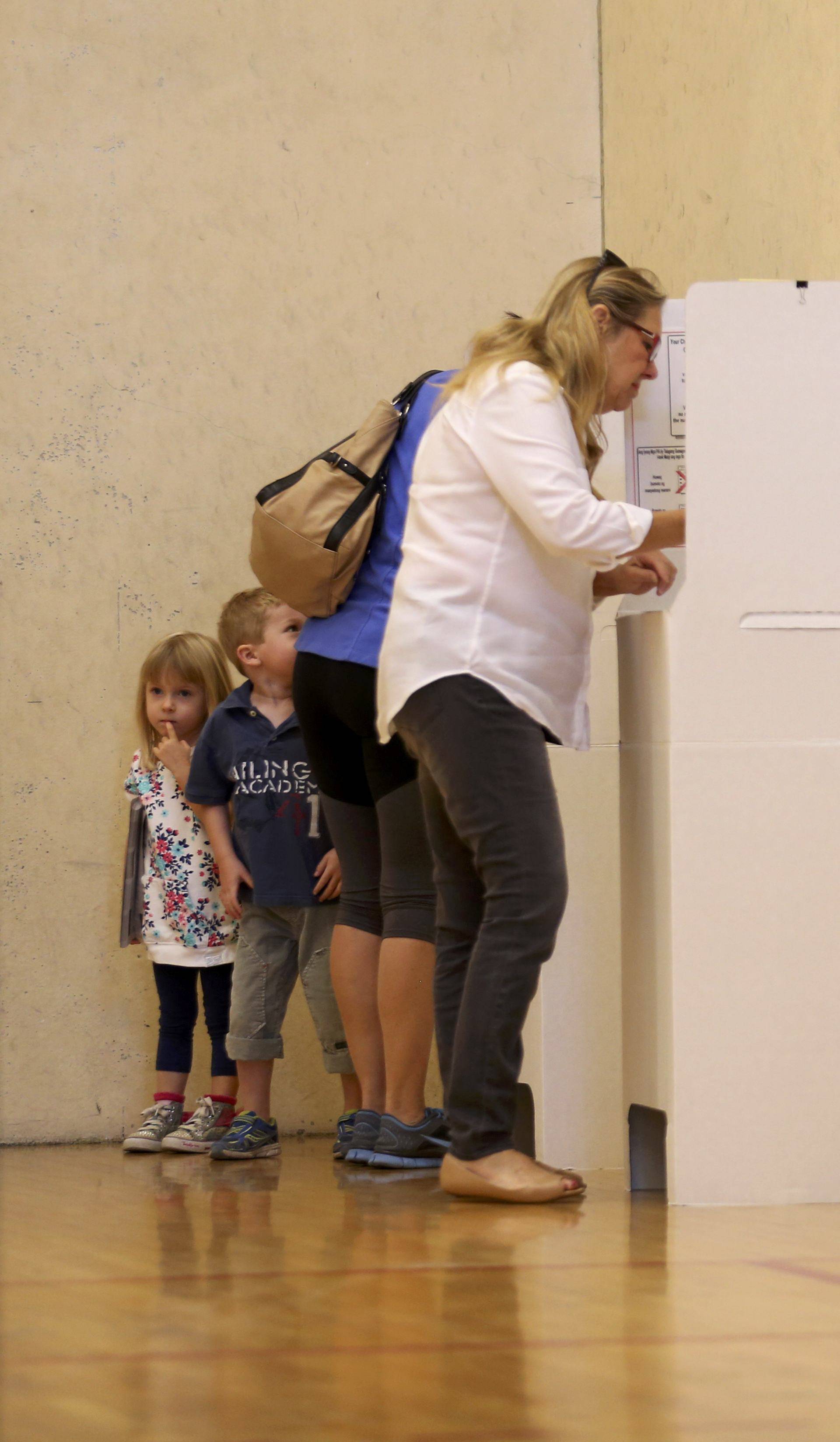 A mother casts her ballot with her two kids during voting in the 2016 presidential election in San Diego, California