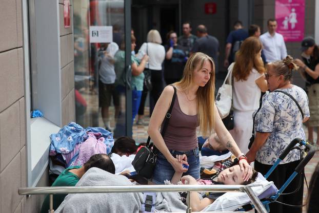 A woman touches a patient near Ohmatdyt Children's Hospital that was damaged during Russian missile strikes, in Kyiv