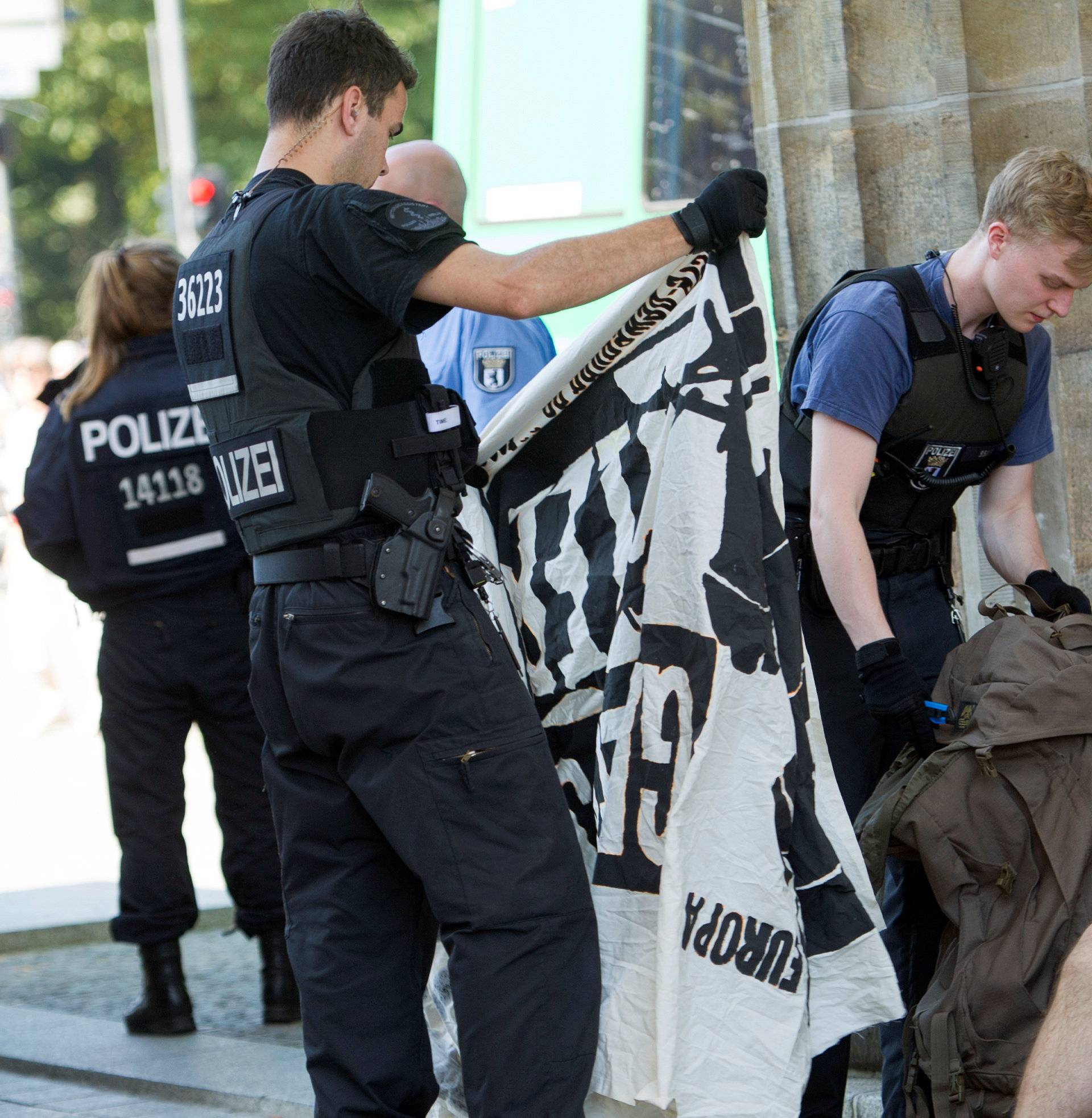 A German police officer looks at a banner belonging to members of far right Identitarian movement  after the activists staged a demonstration on top of Brandenburg Gate in Berlin