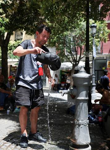FILE PHOTO: A man rinses his hat with water to cool off during a hot day amid a heatwave in Madrid, Spain