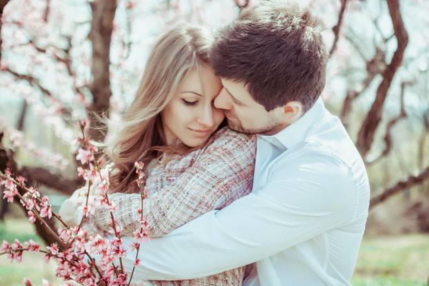 Young Happy Couple in Love Outdoors. Loving Man and Woman On A Walk at Spring Blooming Park