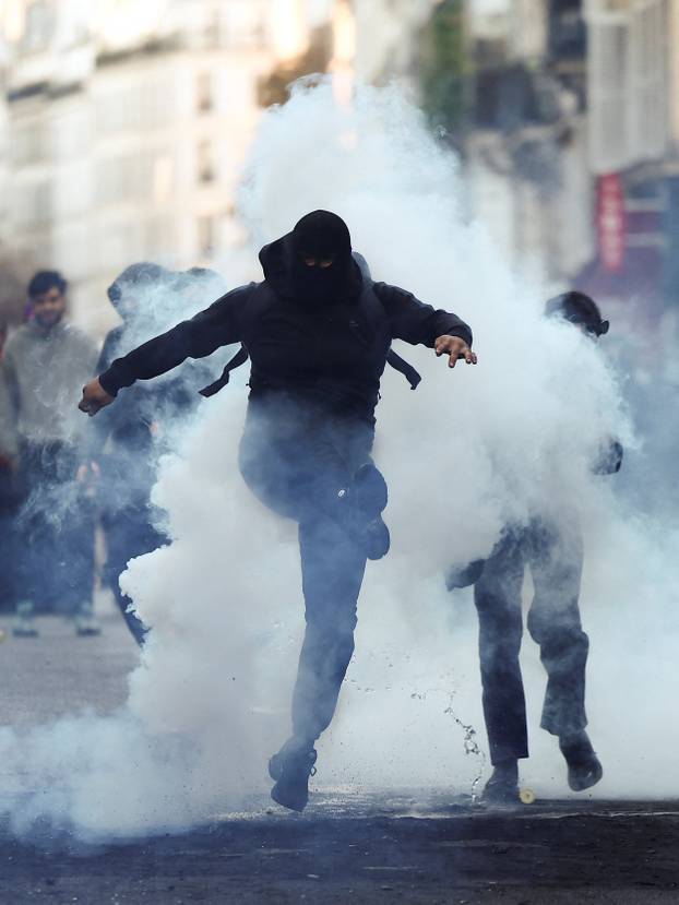 Demonstrators react amid tear gas, the day after a national day of demonstrations against the cost of living and rising fuel prices, in Paris