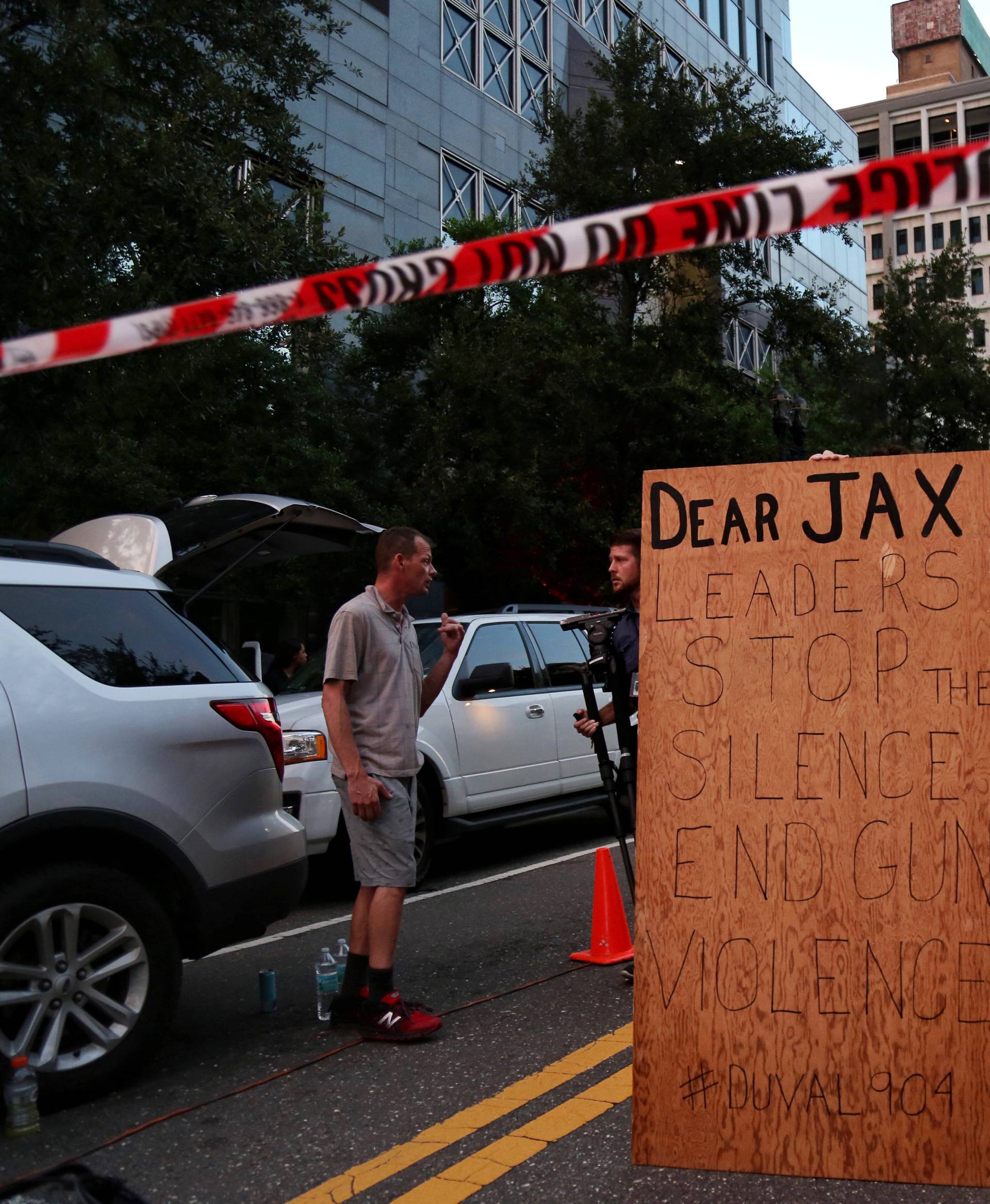 A man holds a sign in support of gun control outside of The Jacksonville Landing after a shooting in Jacksonville