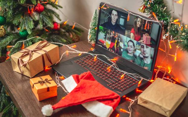 Gift boxes, Santa's hat and a laptop with video chat on the table. Concept of celebrating Christmas with family remotely