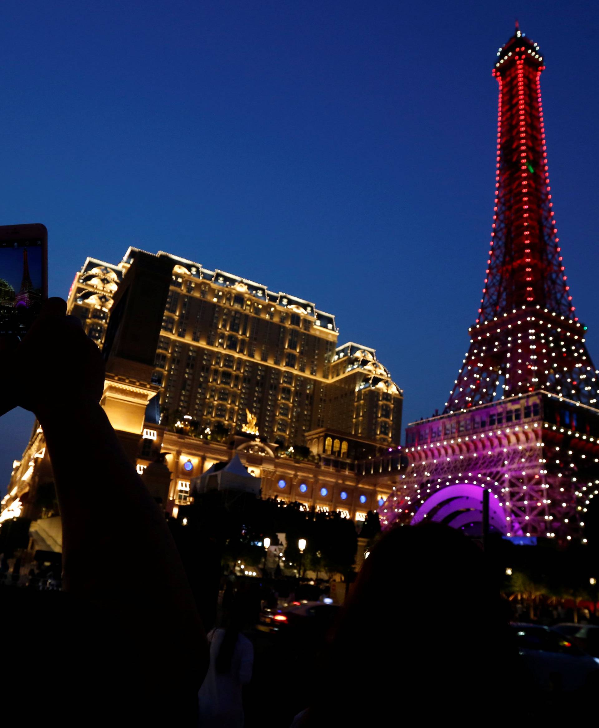 A man takes a photo of a replica of Eiffel Tower outside Parisian Macao as part of the Las Vegas Sands development in Macau