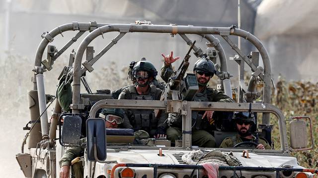 Israeli soldiers sit in a military vehicle, near the border with Gaza in Israel