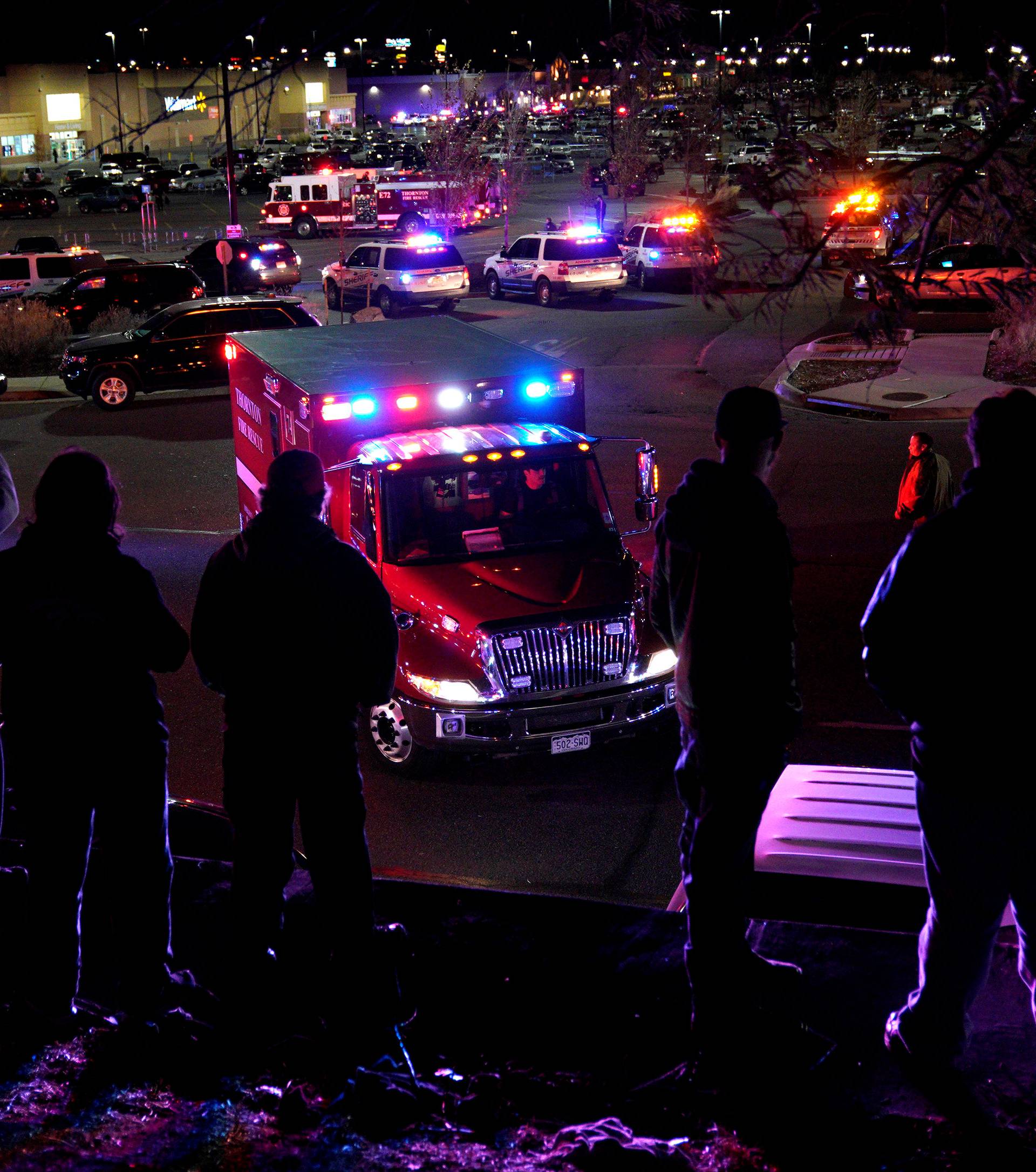 People watch an ambulance leave at the scene of a shooting at a Walmart in Thornton