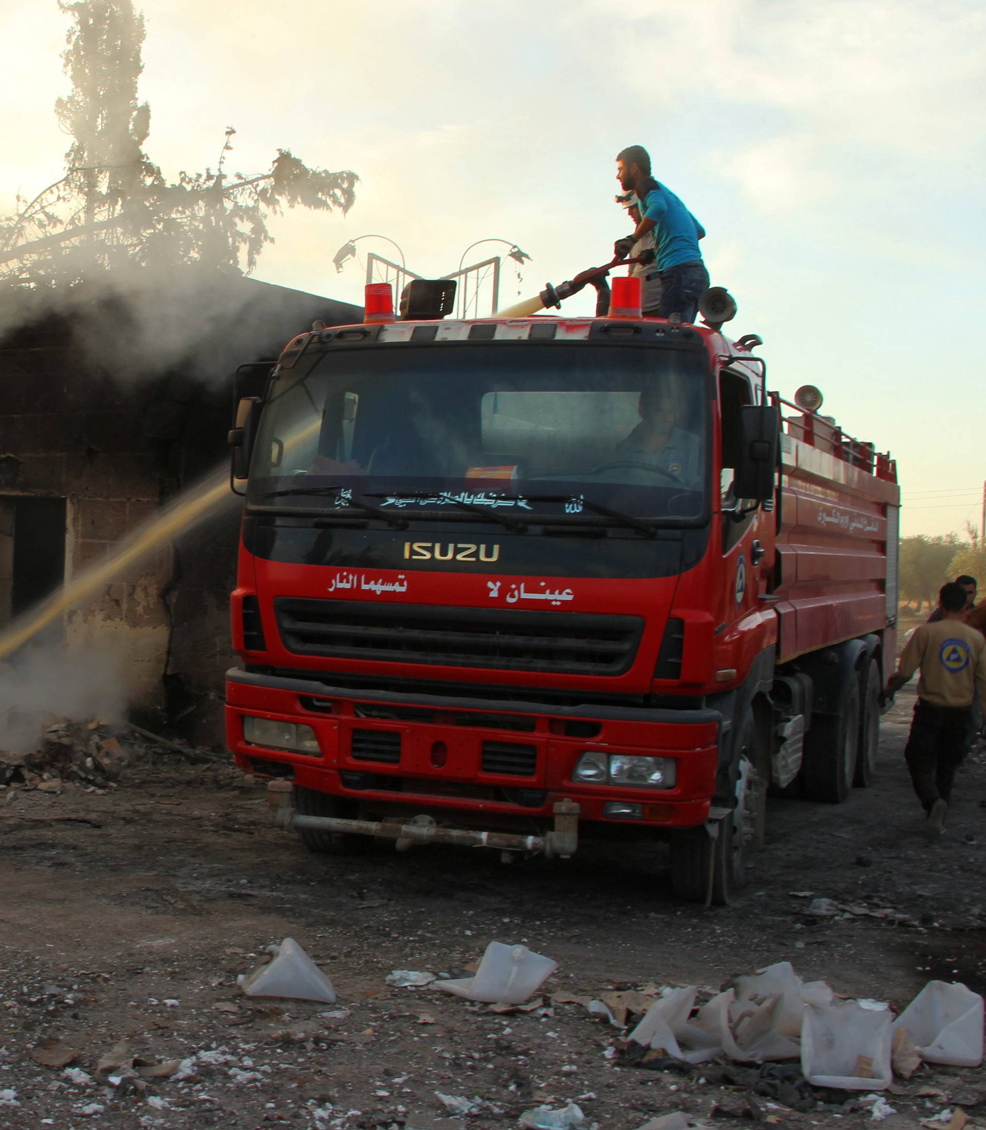 A Civil Defence member and a man put out a fire after an airstrike on the rebel held Urm al-Kubra town